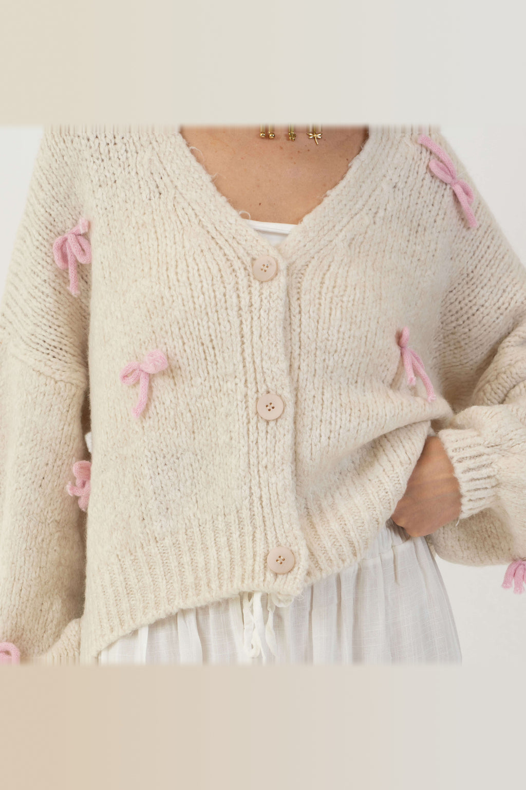 Cárdigan oversize con lacitos en crema con lazos rosa