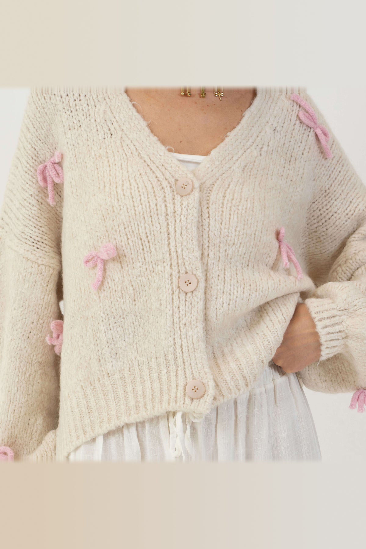 Cárdigan oversize con lacitos en crema con lazos rosa