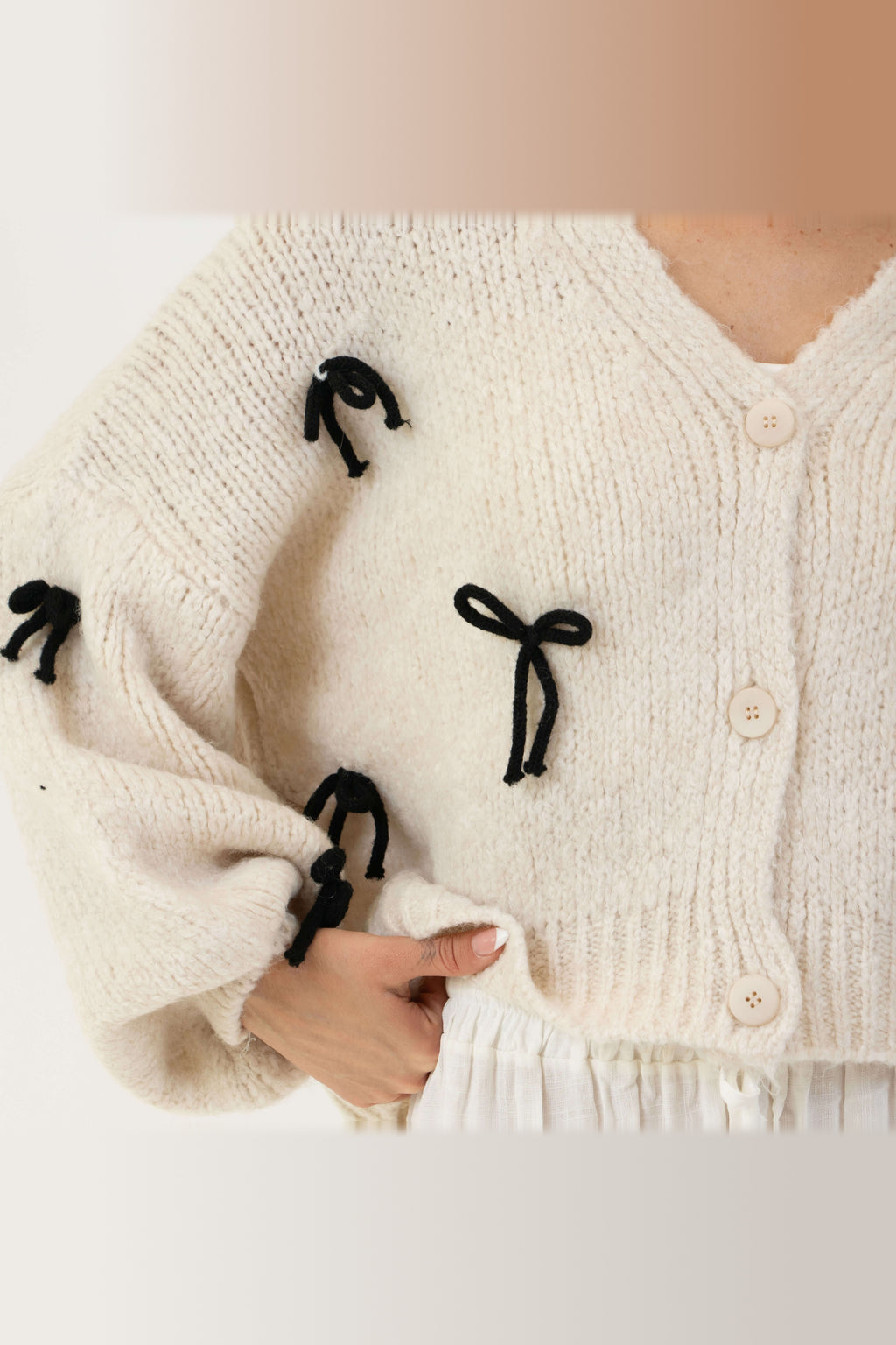 Cárdigan oversize con lacitos en crema con lazos negros
