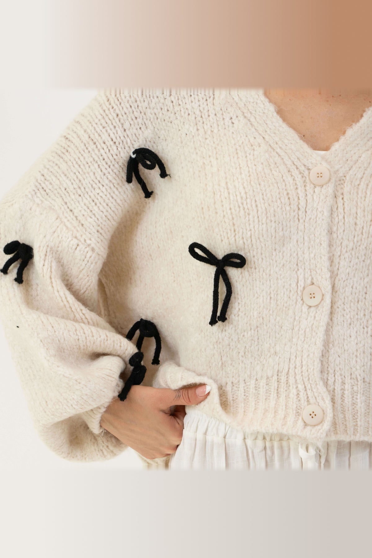 Cárdigan oversize con lacitos en crema con lazos negros